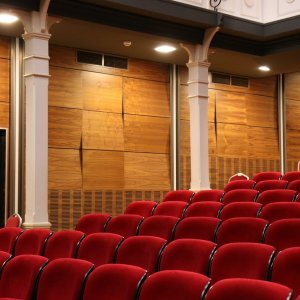 Photo of an empty theatre with red chairs.