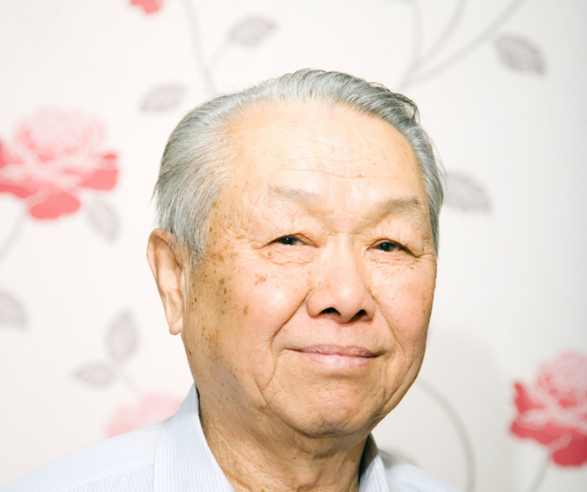 Asian older man with floral background and blue shirt