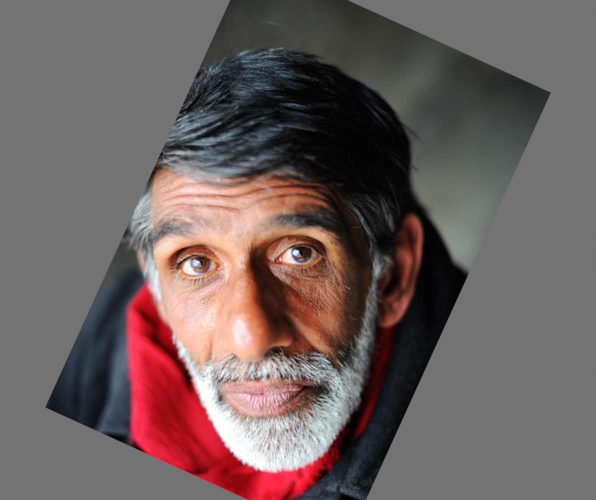 picture of older man with grey beard and brown skin looking up at the camera